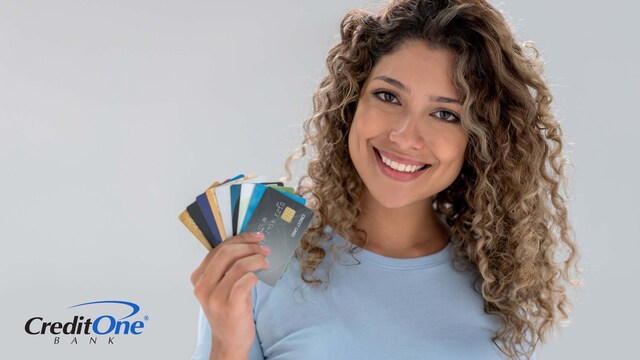 A smiling woman holds a fan of multiple credit cards which she uses for maximum rewards.