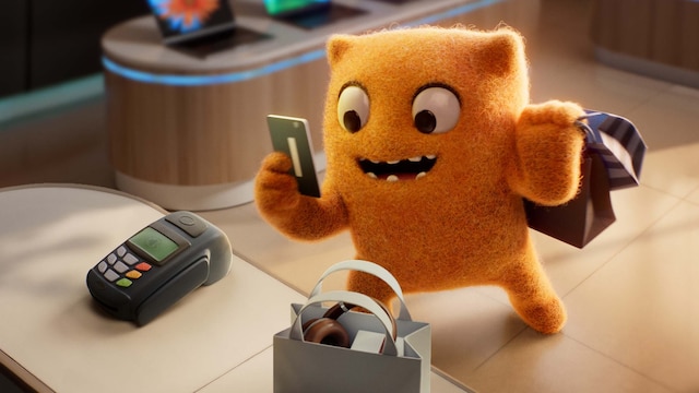 Max Out at the register holding a credit card to complete his shopping purchase