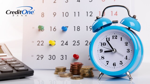 An alarm clock, calculator and pile of coins are in front of a paper calendar, which has color-coded push pins placed at various dates. These objects represent the various aspects of recurring billing.