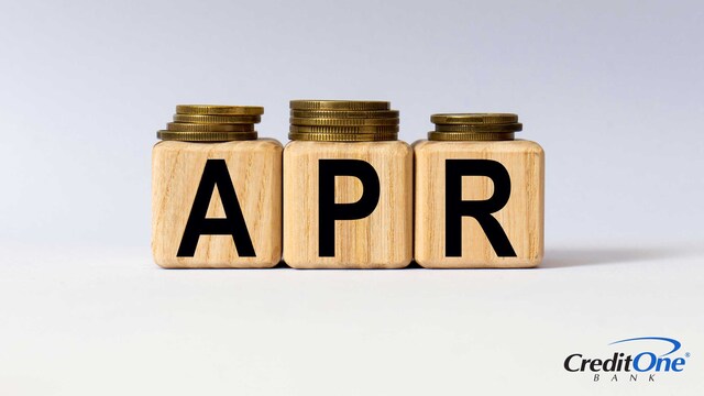 Stacks of coins in various heights sit on top of three wooden blocks spelling out APR, which represents how a credit card APR may get higher based on various criteria.